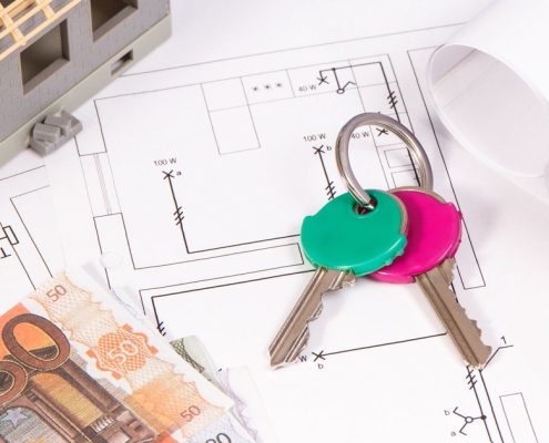 Plan de construction, clés et billets d'euros posés sur un bureau pour illustrer les démarches administratives d'un projet de toiture