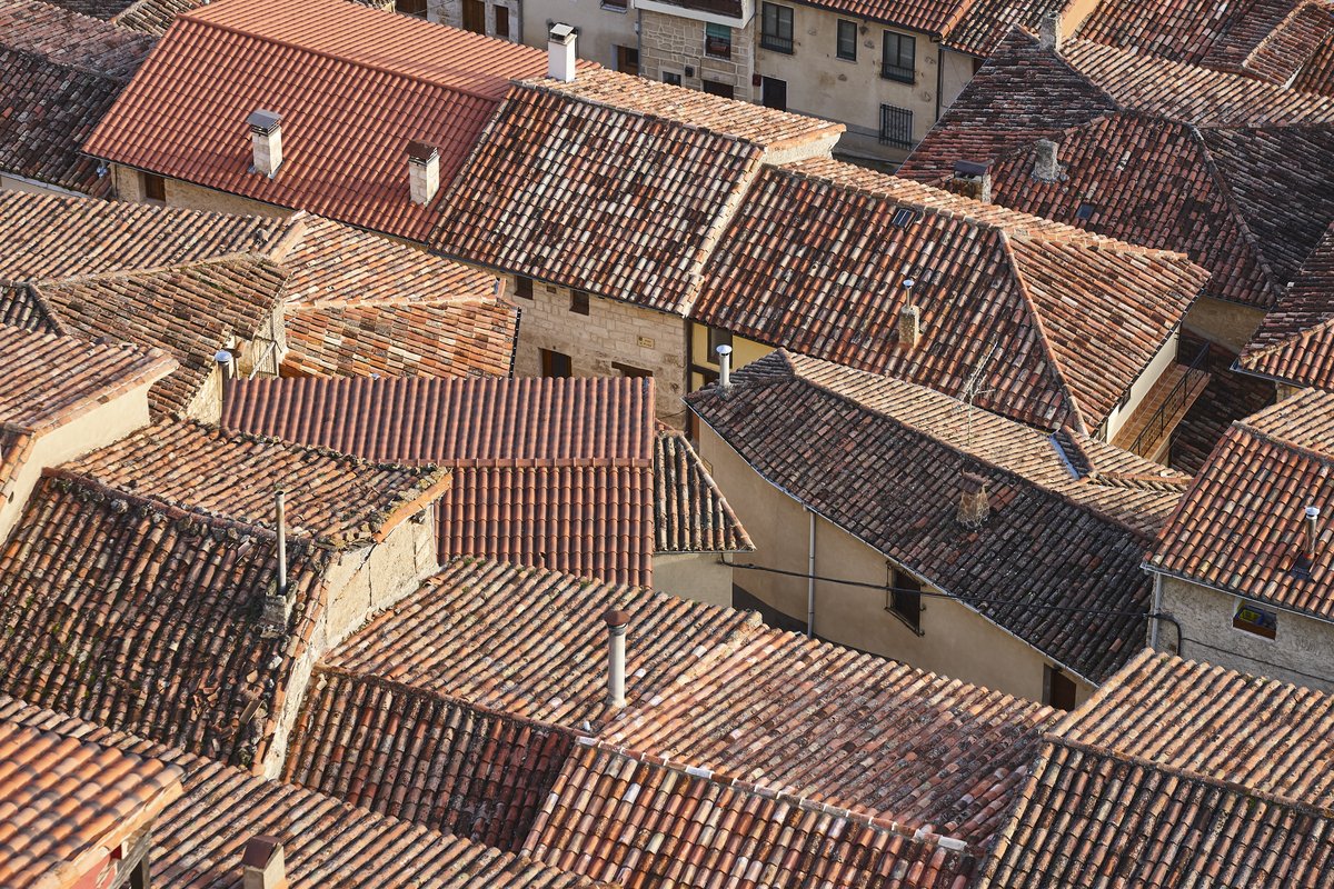Vue aérienne de toitures en tuiles canal dans un centre historique soumis à des règles ABF en région méditerranéenne